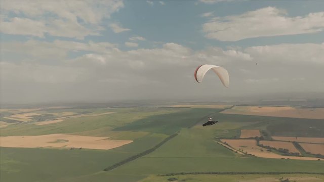 Athlete paraglider flies on his paraglider next to the swallows. Follow-up shooting from the drone