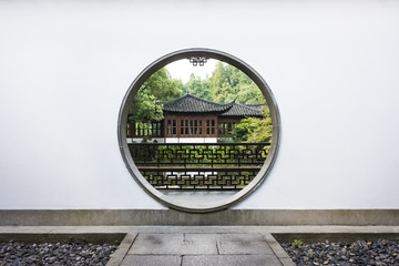 Traditional Chinese house viewed through a circular moon gate in a Chinese garden