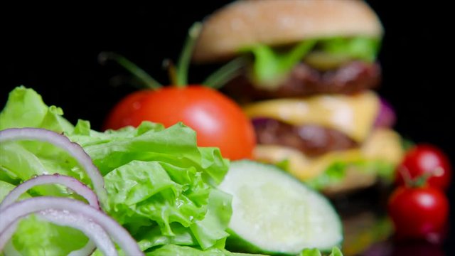 Close up of fresh greens and delicious burger. Black background for commercial use