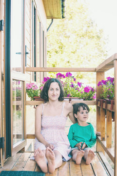 A woman with a child is sitting on the veranda.