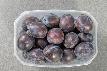 Plastic box full of ripe plums