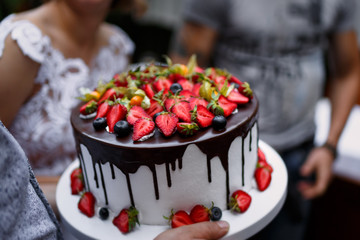 A man bears a beautiful cake at celebration.