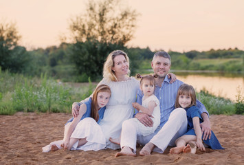 happy family sitting on sand by river