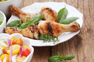 Grilled chicken legs with rosemary served on white plate. Dinner background