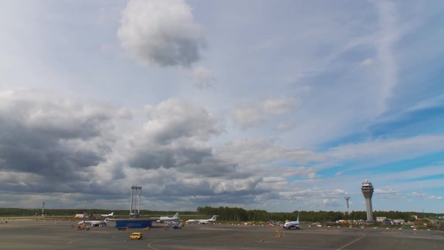 The planes are standing at the airport waiting for their turn to take off. Around the cars of technical airport services