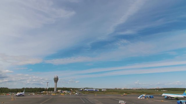 The planes are standing at the airport waiting for their turn to take off. Around the cars of technical airport services