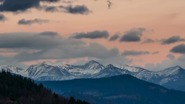 Panoramic view of colorful evening sky over snowy alpine mountains Time lapse