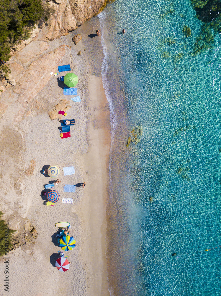 Wall mural Aerial view of an emerald and transparent Mediterranean sea with a white beach full of beach umbrellas and tourists who relax and take a bath. Costa Smeralda, Sardinia, Italy. - Wall murals