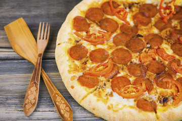 round pepperoni pizza with tomatoes and Mozzarella cheese on an old wooden table