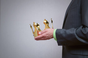 Businessman king holding in hands a gold crown and giving it to his assignee. Award ceremony...