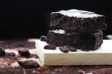 Dark chocolate brownies with almond topping on dark background.