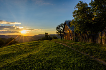 Beautiful sunset over the hills with a wood cabin in a wild country area
