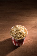 close up view of disposable bucket with popcorn on wooden tabletop