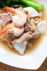 Fototapeta na wymiar Fried noodles with pork , squid , shrimp and kale in gravy sauce