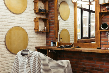 modern barbershop interior and professional barber tools on wooden shelf at mirror