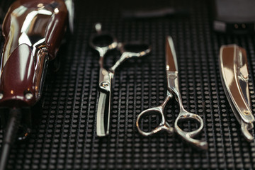 close-up view of scissors, electric clipper and straight razor in barbershop