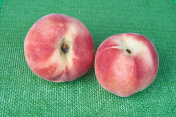 Ripe delicious peach fruit on a green wicker cloth