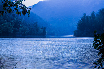 Beautiful lake of renuka in the daytime with blue colour in between mountains around the trees at Nahan