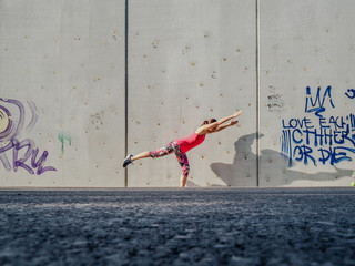 fitness lady making balance Pose outdoor infront of a grey cement wall as background