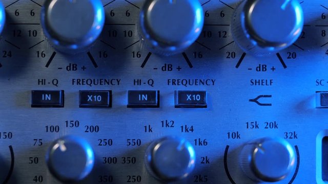 Adjustable handles on the compressor panel in professional recording studio. Blue neon light. Sound mixing concept. Dolly shot. 4k.