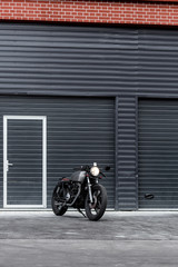 Custom motorcycle parking near dark industrial building. Everything is ready for having fun driving the empty road on a motorcycle tour journey. Hipster city hobby. Space for your individual text.