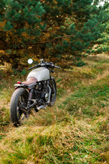 Fototapeta na wymiar Silver caferacer motorbike parking on a country road. Everything is ready for having fun after hard day in office. Modern young businessman hipster hobby. Space for your individual text.