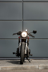 Vintage motorbike parking near gray wall of finance building. Everything is ready for having fun driving the empty road on a motorcycle tour journey. Businessman hobby. Space for your individual text. - 214189526