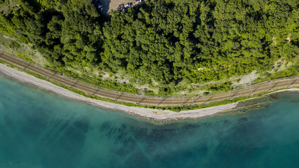 Aerial stock photo of car driving along the winding mountain pass road through the forest in Sochi, Russia. People traveling, road trip on curvy road through beautiful countryside scenery.
