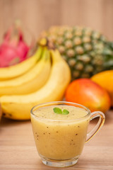 Tropical fresh fruit set and juice smoothies isolated with wooden background