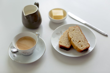 Afternoon tea setting on a white background with banana cake and butter