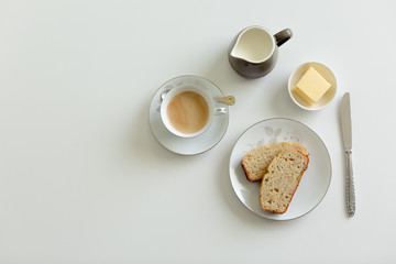 Afternoon tea setting on a white background with banana cake and butter
