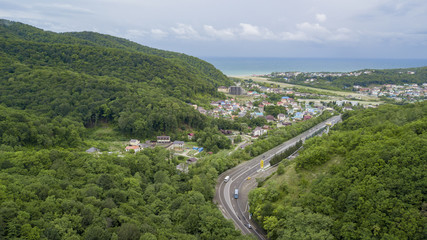 Fototapeta na wymiar Aerial stock photo of car driving along the winding mountain pass road through the forest in Sochi, Russia. People traveling, road trip on curvy road through beautiful countryside scenery.