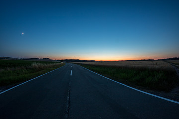 Straße durch Felder im Sonnenuntergang