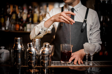 Bartender stirring fresh summer alcoholic cocktail in glass
