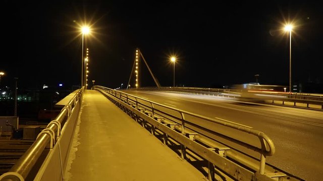 Timelapse of traffic on an bridge at night. The bridge it lit by warm street lights and the headlights of passing cars. Shot in Ultra High Definition. In the European city of Ulm.