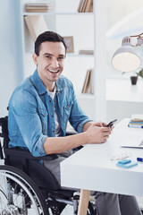 Look at me. Joyful disabled man expressing positivity while sitting on his wheelchair