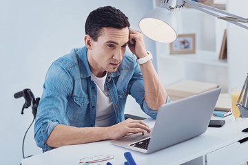 Creating plan. Concentrated young man wrinkling forehead while working with computer