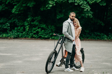 Smiling couple hugging near the modern bicycle in park. Love and tenderness, dating, romance. Lifestyle concept