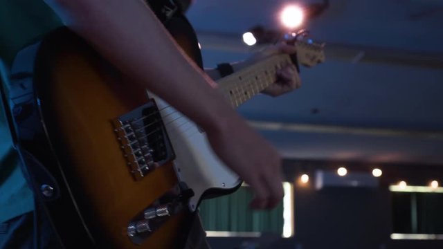 Guitarist strumming a tobacco colored telecaster at an indoor venue