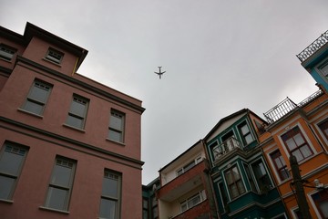 Fototapeta na wymiar A plane is flying low over Balat houses