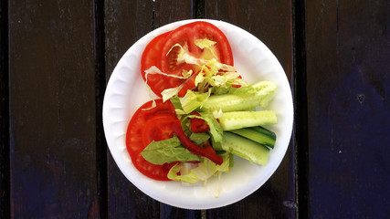 View from above. A plate with chopped vegetables rotates on a wooden table.