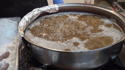 The cook puts meat balls in boiling oil.