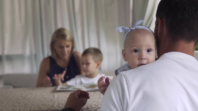 Father holds baby daughter, girl look at camera