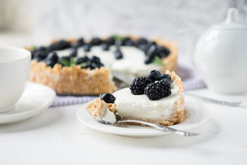 Piece of cheesecake with blueberries and blackberries with white service