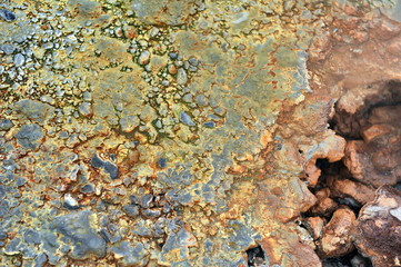 Multicolored smooth stones around the smoking fumarole