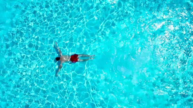 View from the top as a man jumping and dives into the pool and swims under the water
