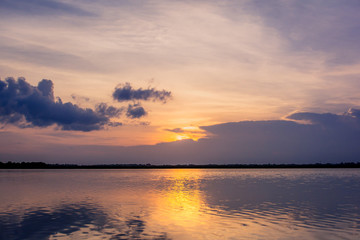 Sunset in the lake. beautiful sunset behind the clouds above the over lake landscape background