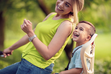 Fototapeta premium Young mother and boy biking at summer warm day.