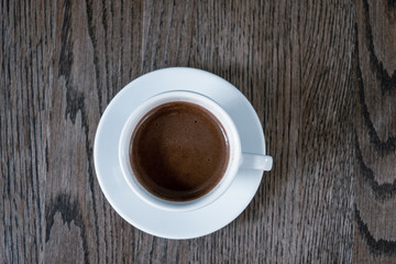 Cup of coffee on wooden table, top view