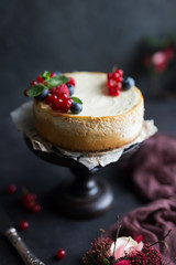Homemade cheesecake with fresh berries on a dark wooden stand.